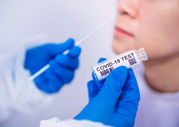 Doctor in protective gloves & workwear holding Testing Kit for the coronavirus test