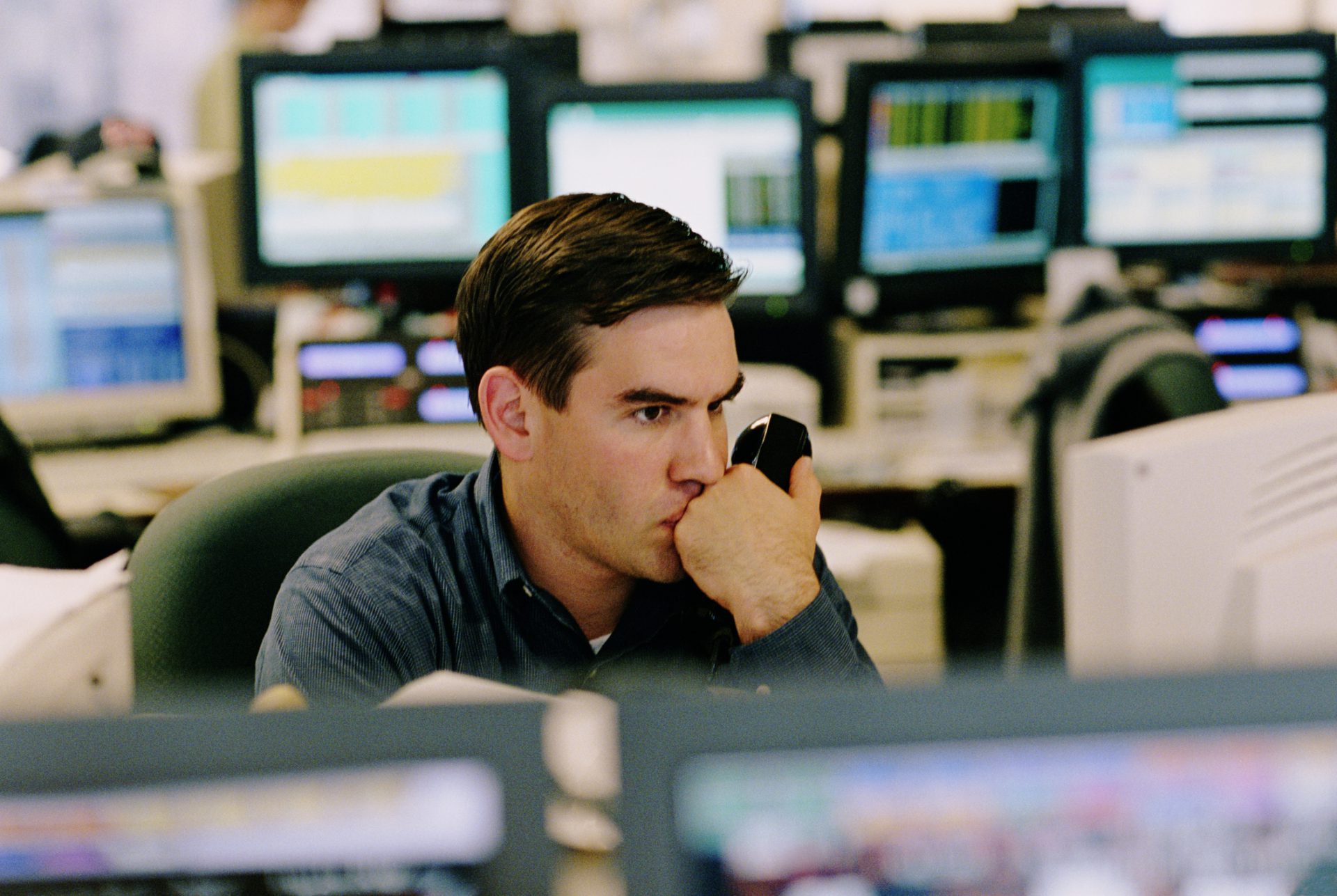 BROKER WATCHING STOCK AND HOLDING PHONE