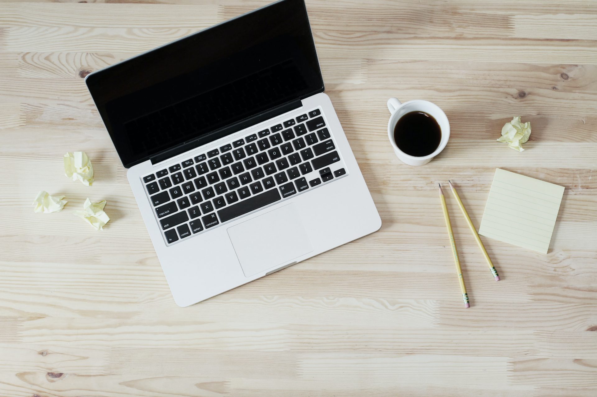 turned off Mac Book Pro next to white ceramic mug filled with coffee