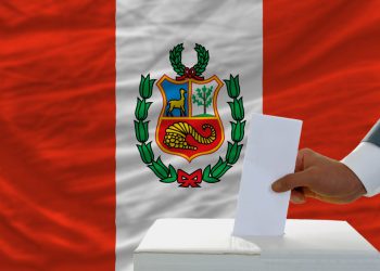 man voting on elections in peru front of flag