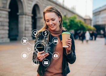 Beautiful young woman using a smartphone with various icons of smart technology.