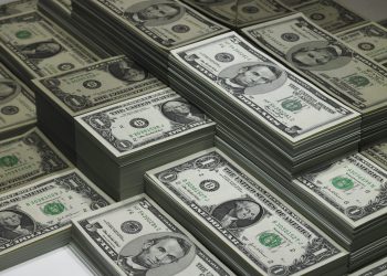 piles of dollar bills reflected in glass