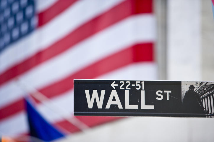Sign on Wall Street and American flag.