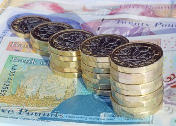 Five stacks of newly minted one pound coins arranged in increasing height on British pound notes.