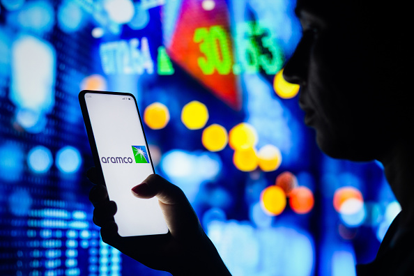 BRAZIL - 2022/04/04: In this photo illustration, a woman's silhouette holds a smartphone with the Saudi Arabian Oil Company (Aramco) logo displayed on the screen. (Photo Illustration by Rafael Henrique/SOPA Images/LightRocket via Getty Images)