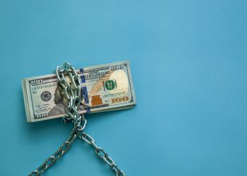 Hundred dollar bills wrapped in a chain on a blue background. Concept of economy, finance and exchange rate