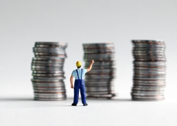 A miniature man reaching for a pile of three coins.