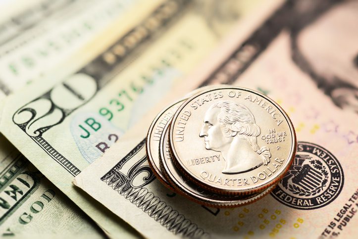 Stack of 25 US cents or quarters coins with some dollar bills
